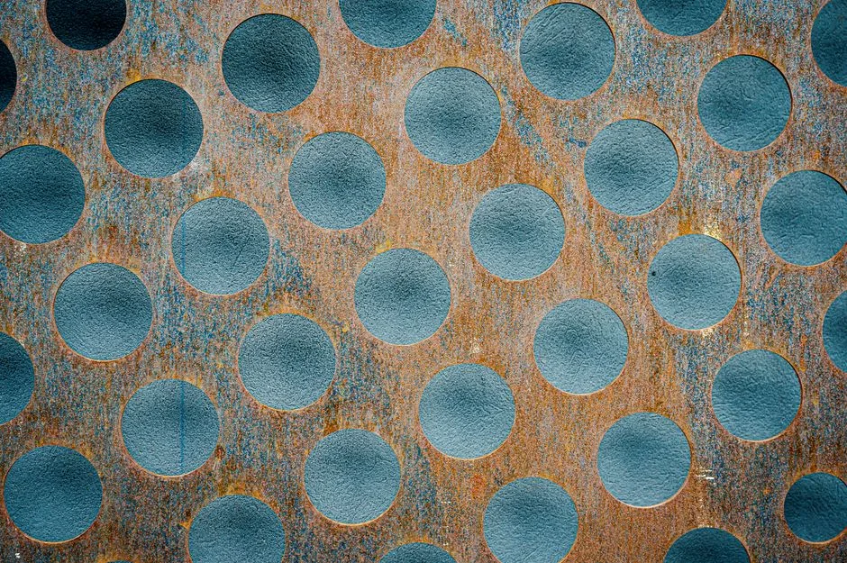 Close-up of a metallic grille with a uniform circular pattern — similar to baffle filter construction